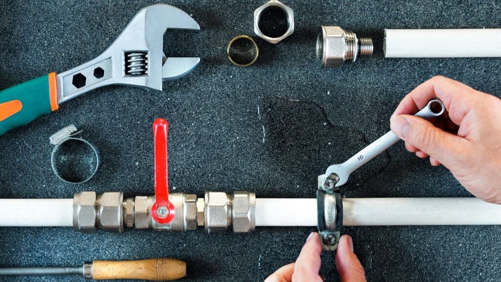 Plumber repairing a pipe valve with an adjustable wrench in Hemet