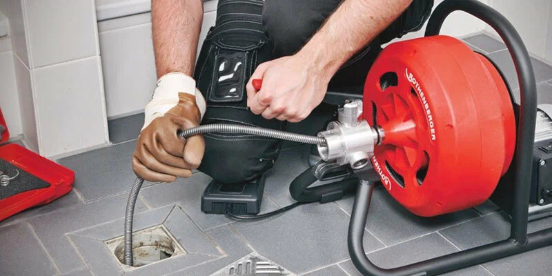 Plumber using a drain-cleaning machine in Hemet