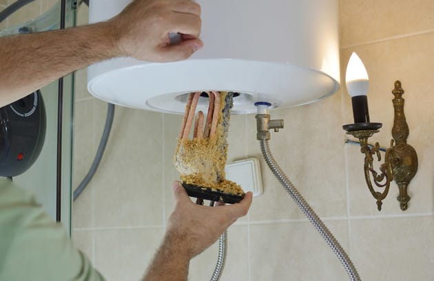 Technician removing mineral buildup from a water heater in Hemet