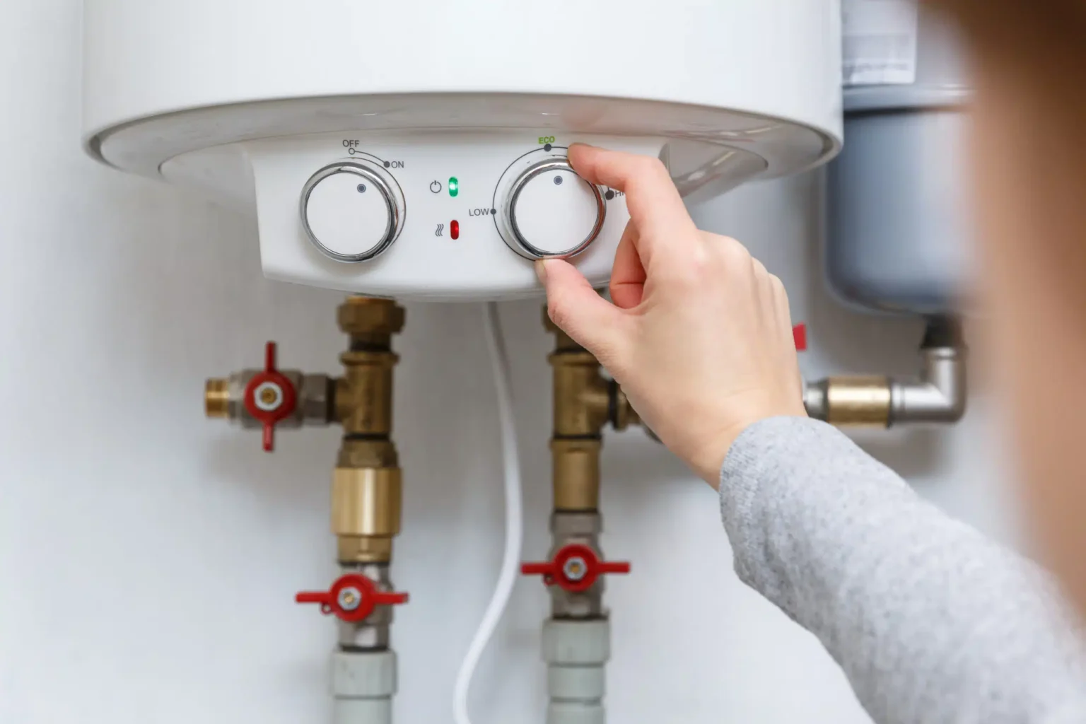 Homeowner adjusting the temperature controls on a water heater in Hemet